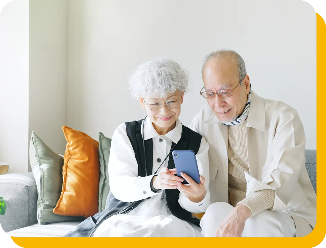 自宅でスマートフォンの操作を確認する高齢の夫婦